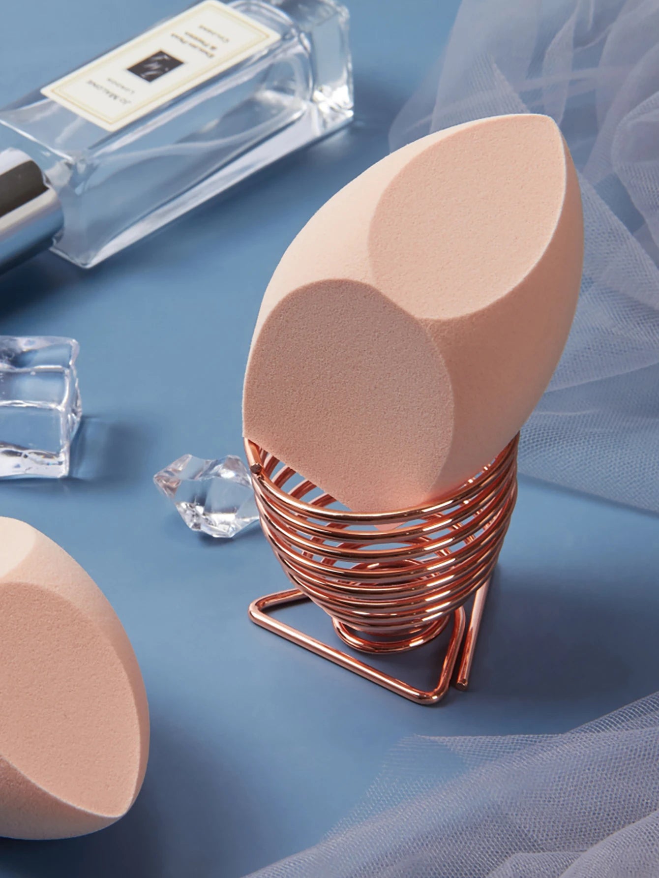 1 Pack Big Size Makeup Sponge Foundation Cosmetic displayed on a soft blue surface with ice cubes and a copper holder.