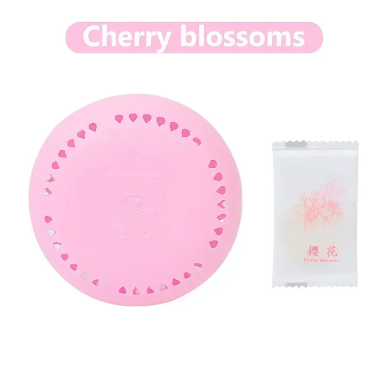home fragrance solid air freshener in a cherry blossoms scent, pink circular design with a sachet package